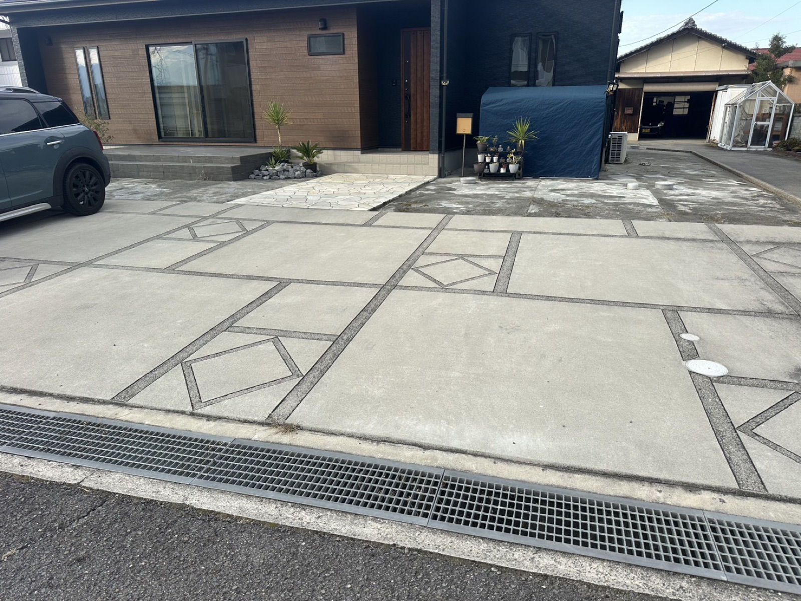 デザイン目地を入れた土間コンクリートの駐車場と、平屋の住まい